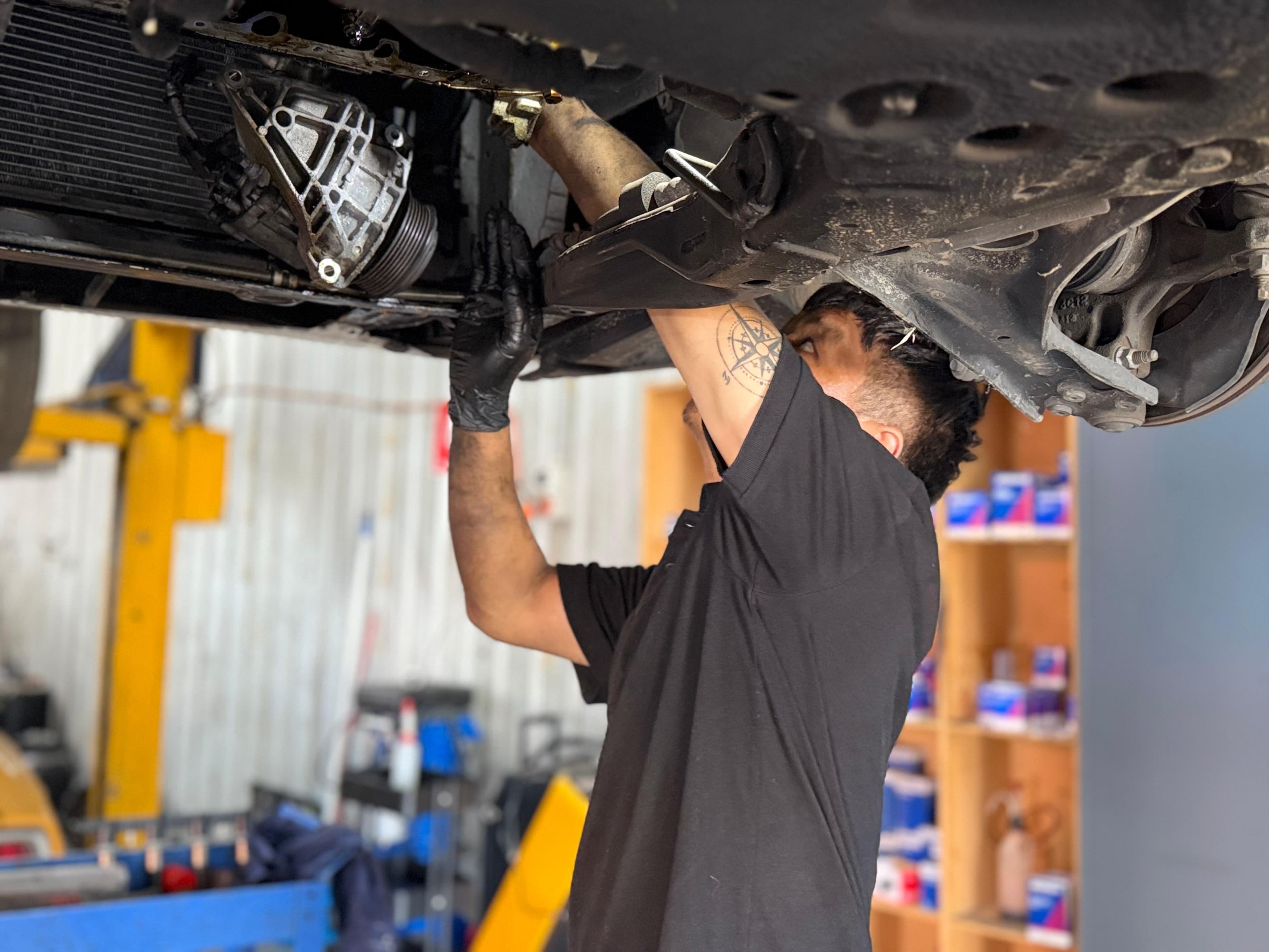 Technician working underneath a raised vehicle in the workshop
